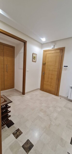 Una habitación con suelo de baldosas, un armario de madera y una puerta.
