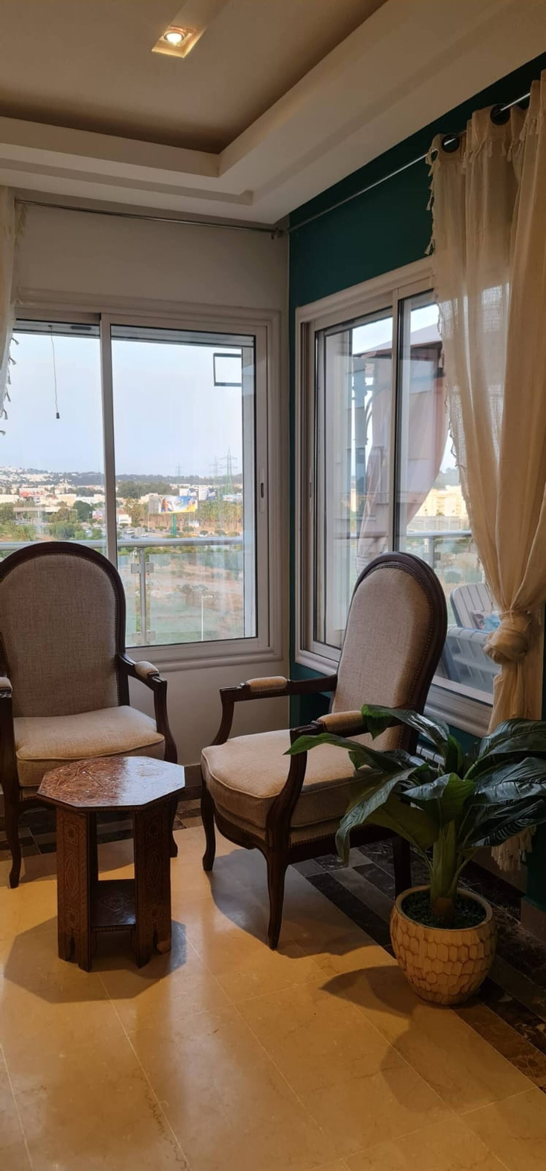 A room with two chairs, a small table, and a potted plant.