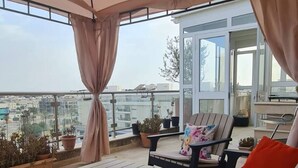 A covered outdoor seating area with a table and lounge chairs, overlooking a cityscape. - Luxurious 3-bedroom Apartment in Heart of Tunis (Tunis)