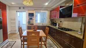 A compact kitchen with a microwave, stove, and sink. - Luxurious 3-bedroom Apartment in Heart of Tunis (Tunis)