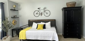 A bedroom with a bed, a dresser, a bicycle wall art, and a potted plant. - Resort-Style 
Backyard Retreat 
Pool-Spa & Firepit (Garden Ridge)