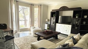 Un salon comprenant un canapé, une table basse, un téléviseur et un meuble.