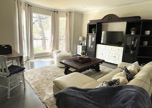A living room with a sofa, a coffee table, a TV, and a cabinet. - Resort-Style 
Backyard Retreat 
Pool-Spa & Firepit (Garden Ridge)
