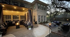 An outdoor patio area with a seating arrangement, a fire pit, and a large building in the background. - Resort-Style 
Backyard Retreat 
Pool-Spa & Firepit (Garden Ridge)