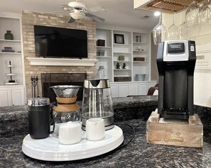 Uma bancada de cozinha com cafeteira, chaleira, jarra de café e caneca.