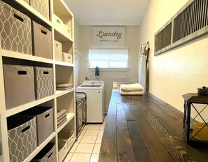 A laundry room with a washing machine, drying rack, and storage bins. - Resort-Style 
Backyard Retreat 
Pool-Spa & Firepit (Garden Ridge)