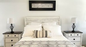 A bedroom with a white bed, two nightstands, a framed quote on the wall, and a patterned bedspread. - Resort-Style 
Backyard Retreat 
Pool-Spa & Firepit (Garden Ridge)