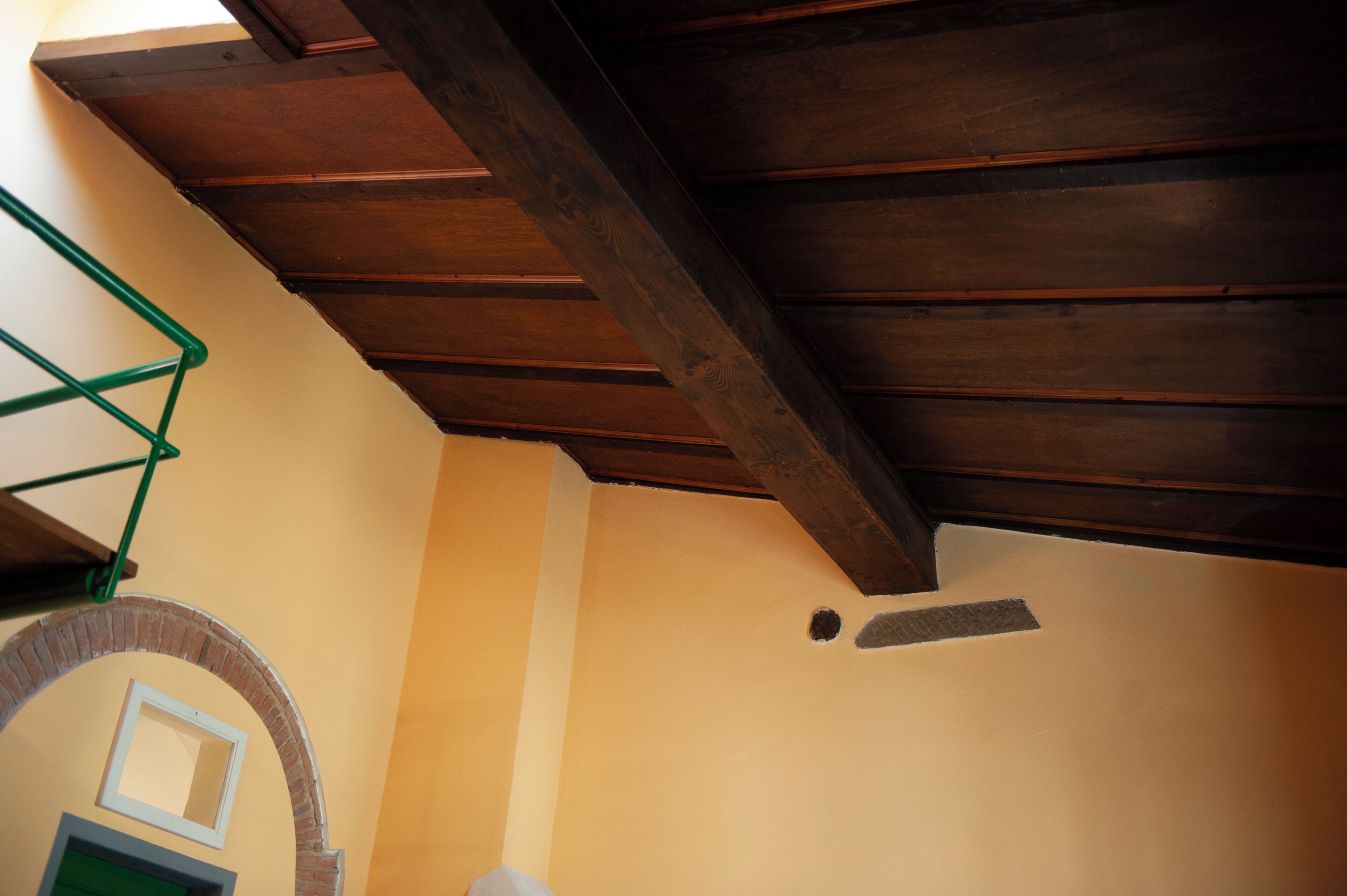 Une pièce dotée d’un plafond en pente, d’une arche en briques et d’une structure métallique verte.