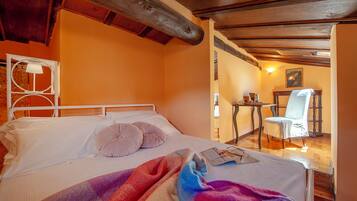Une chambre à coucher avec un lit, des oreillers, une table de chevet, une chaise et un tableau au mur.