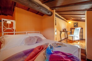 Une chambre à coucher avec un lit, des oreillers, une table de chevet, une chaise et un tableau au mur.