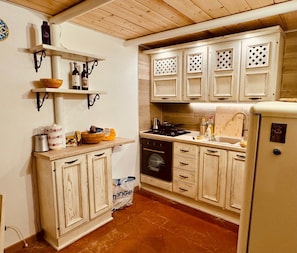 A kitchen with wooden cabinets, a stove, and a refrigerator. - Terrazzino San Frediano - Flo Apartments (Florence)