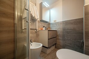 Ein modernes Badezimmer mit einer Duschkabine aus Glas, einem weißen Waschbecken und einem Waschtisch mit Stauraum.