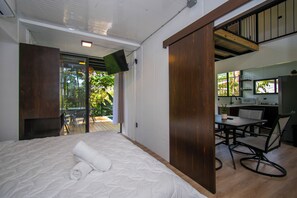 A bedroom with a bed, a desk, and a view of a balcony. - Casa Bamboo, Peaceful 3 bdr Jungle Home in Uvita, 2min from river and waterfalls (Uvita)