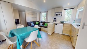 A compact kitchen with a dining area, a microwave, a coffee maker, and a sink. - Sun & Pool: 3-bedroom mobile home, patio & pool (Saint-Hilaire-de-Riez)
