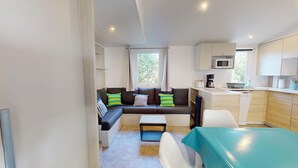 A compact living space with a sofa, a small dining table, and a kitchenette. - Sun & Pool: 3-bedroom mobile home, patio & pool (Saint-Hilaire-de-Riez)