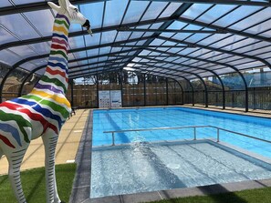 A swimming pool with a transparent roof structure and a colorful giraffe statue. - Sun & Pool: 3-bedroom mobile home, patio & pool (Saint-Hilaire-de-Riez)