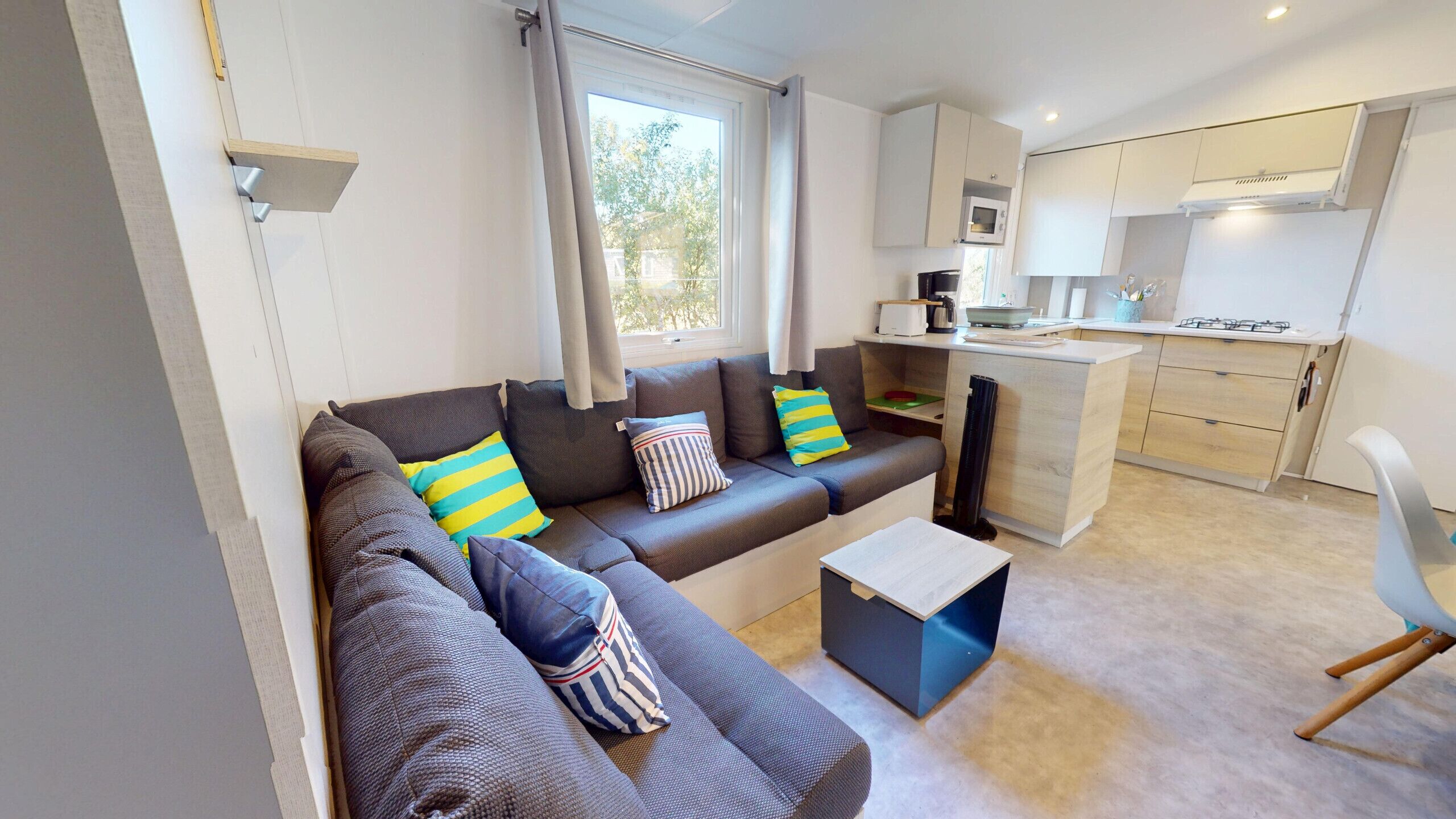 A modern living room with a sofa, a coffee table, and a view of a kitchen area.