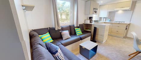 A modern living room with a sofa, a coffee table, and a view of a kitchen area.