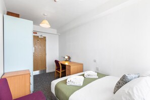 Ein Hotelzimmer mit Bett, Schreibtisch, Stuhl, Schreibtischlampe und einem Rauchverbot-Schild an der Tür.