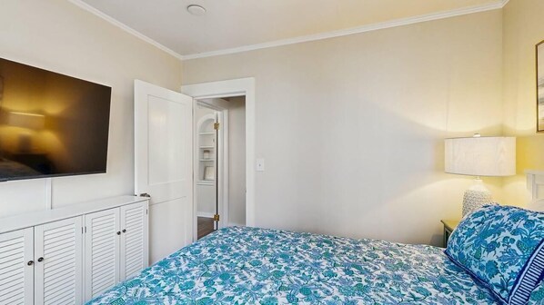 A bedroom with a bed, a television, a wardrobe, and a door leading to a bathroom.