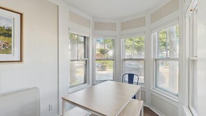 A corner room with a table and a chair, large windows, and a framed picture on the wall. - Walk to Ferry & Beach from Central Oak Bluffs (Oak Bluffs)