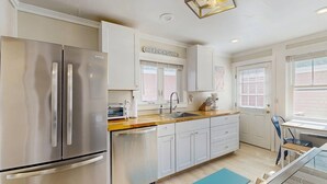 A modern kitchen with stainless steel appliances, white cabinetry, and a window with blinds. - Walk to Ferry & Beach from Central Oak Bluffs (Oak Bluffs)