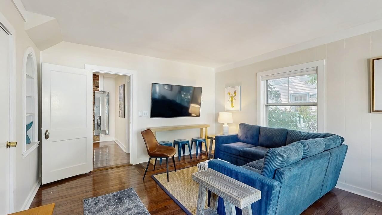 A living room with a blue sofa, a television, and a window.