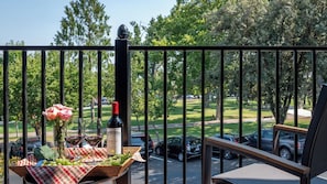 A balcony with a table set for a meal, a bottle of wine, and a vase of flowers. - Paso Park Suites by Avantstay 2 Private Balconies + Town Square Views Downtown Paso Robles (Paso Robles)