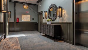 A hallway with a wooden bench, a map on the wall, and an elevator. - Paso Park Suites by Avantstay 2 Private Balconies + Town Square Views Downtown Paso Robles (Paso Robles)