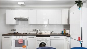 Eine moderne Küche mit weißen Schränken, einem Backofen, einer Waschmaschine und einem Kühlschrank.