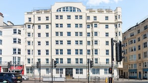 Ein mehrstöckiges Gebäude mit einer symmetrischen Fassade, großen Fenstern und einem zentralen Eingang.