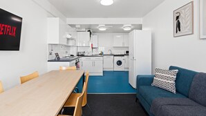 Kompakti oleskelutila, jossa on pieni keittiönurkkaus, ruokailualue ja sohva.