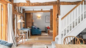 A rustic interior with exposed wooden beams, a staircase, a dining area, and a living room. - Medleys Barn | By My Getaways (High Hurstwood)