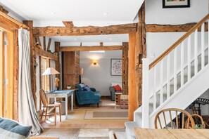 A rustic interior with exposed wooden beams, a staircase, a dining area, and a living room. - Medleys Barn | By My Getaways (High Hurstwood)