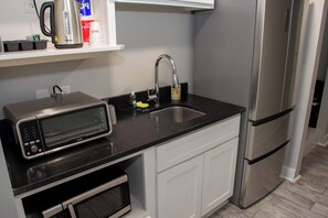 Eine Küche mit Mikrowelle, Kaffeemaschine, Spüle und Kühlschrank.