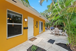 A yellow building with a covered patio area, outdoor seating, and a door marked with the number 2. - Private 2BR Beach House - Walk to the Beach (Lauderdale-by-the-Sea)