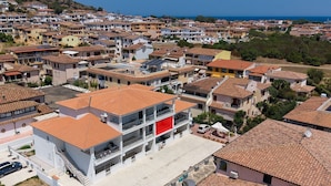A residential area with multiple two-story buildings, a parking lot, and a clear view of the sea. - Pegaso - Two Bedroom Apartment, Sleeps 5 (La Caletta)