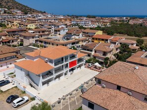 A residential area with multiple two-story buildings, a parking lot, and a clear view of the sea. - Pegaso - Two Bedroom Apartment, Sleeps 5 (La Caletta)