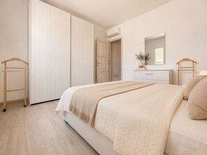 Ein Schlafzimmer mit einem Bett, einem Schminktisch, einem Spiegel und einem Kleiderschrank.