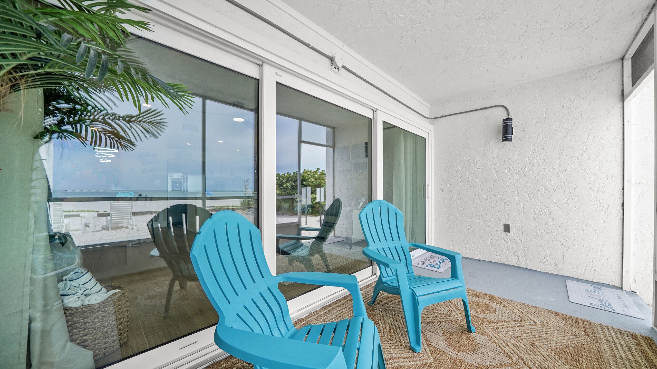 A modern outdoor seating area with two chairs and a glass table, overlooking a scenic view.
