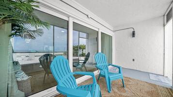 A modern outdoor seating area with two chairs and a glass table, overlooking a scenic view.