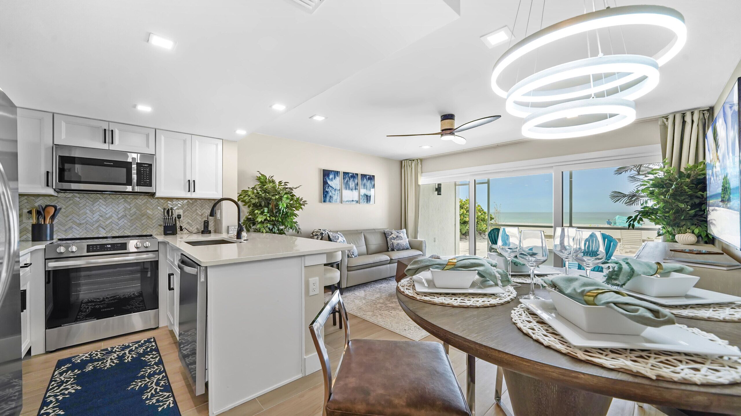 A modern kitchen with built-in appliances, a dining area with a view, and a ceiling fan.