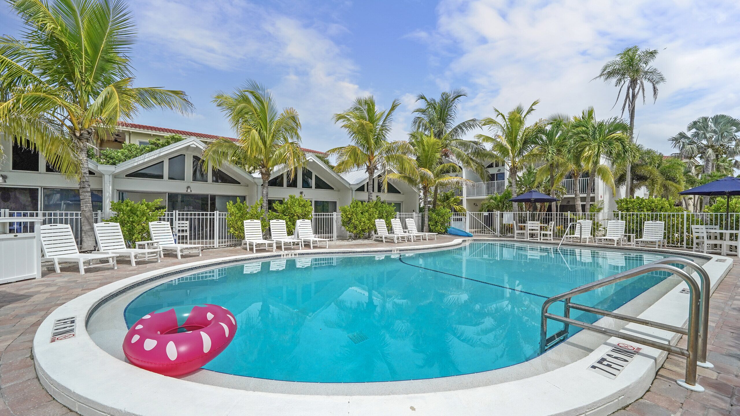 A swimming pool with lounge chairs and palm trees.