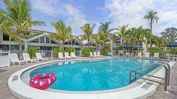 A swimming pool with lounge chairs and palm trees.