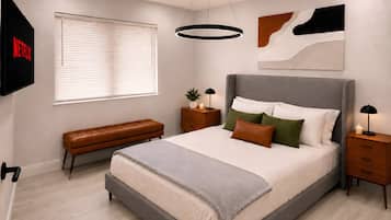 Une chambre à coucher moderne avec un grand lit, des tables de chevet, un banc et un téléviseur fixé au mur.