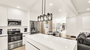 Een moderne keuken met roestvrijstalen apparatuur, een centraal eiland en een eethoek met een ronde tafel.