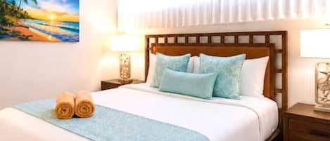 Hotelkamer met een bed, twee bedlampen, een plafondventilator, een schilderij aan de muur en een raam met gordijnen.