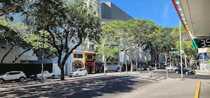 Straßenansicht mit parkenden Autos, Bäumen und Gebäuden.