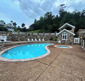 A swimming pool with a stone wall and lounge chairs.