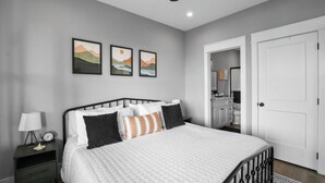 A bedroom with a bed, nightstand, lamp, and wall art.